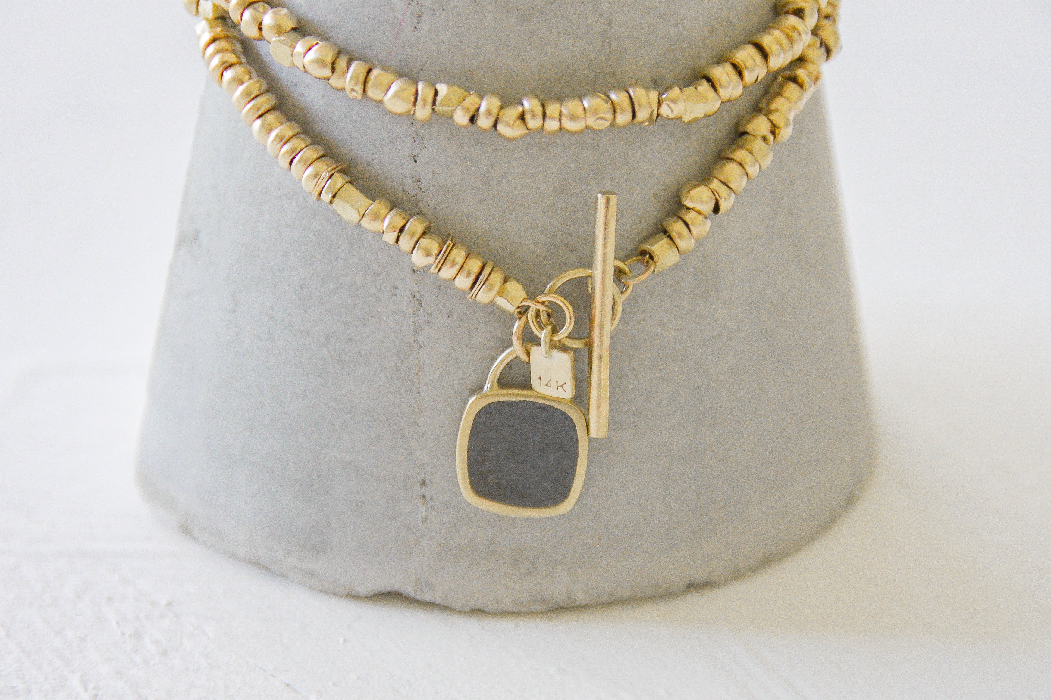 Gold beads necklace with a gold & concrete charm